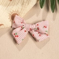Detail einer rosa karierten Stoffschleife mit Kirschmuster für DIY-Haarspangen - Korallenrosa