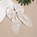 Makroaufnahme einer weißen Chiffon-Haarschleife mit gelben Gänseblümchen und Bändern - Weiß