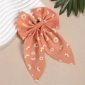Detailaufnahme der orange-rosa Chiffon-Haarschleife mit zartem weißen Gänseblümchen-Print - Koralle