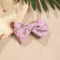 Detailed macro view of purple gingham bow hair accessory with cute red cherry print - Pink Purple