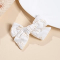 Detail of white cotton bow hair clip with delicate light brown floral embroidery patterns - White