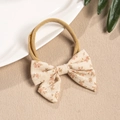 Detail of floral linen bow on stretchy nylon baby headband for children's hair styling - Orange Flower