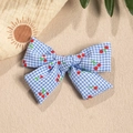 Close-up of blue plaid bow with cherry print on a beach sand background - Blue