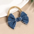 Dettaglio del fiocco in denim blu con ricamo bianco su una fascia elastica in nylon - Stile con Cuciture Ondulate Bianche