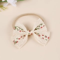 Detail view of baby bow headband with vintage floral embroidery and lace texture - Red and Green Floral