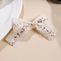 Dettaglio di fermaglio per capelli a fiocco in pizzo bianco con ricami floreali rossi - Piccolo Fiore Rosso
