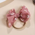 Gros plan détaillé d'un grand nœud en résille rose avec motifs marguerites et bandeau en nylon - Rose Foncé
