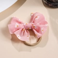 Detail eines rosa Chiffon-Schleifen-Haarbandes mit Gänseblümchen-Muster und Nylonband - Rosa