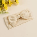 Dettaglio della fascia per neonati in pizzo beige con ricami floreali e fiocco grande - Cachi