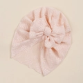 Dettaglio del turbante in pizzo rosa per neonata con trama floreale e grande fiocco - Rosa Chiaro
