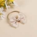 Detail of baby headband featuring cream checkered bow and soft nylon elastic band - Headband Style / Off White
