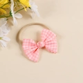 Detail showing pink checkered bow headband with delicate wavy edges and soft elastic band - Headband Style / Bright Pink