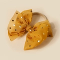 Detailed view of a yellow tulle bow headband with gold dots on a nylon elastic band - Turmeric