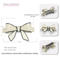 Elegant acrylic bow hair clip in cream with black edging and metal spring fastener - Off White