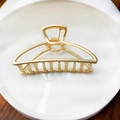 Close-up of matte gold metal hair claw clip with hollow design and fine texture - Matte Gold