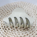 Dettaglio di una pinza per capelli crema con bordi neri su un tappeto intrecciato - Bianco avorio