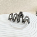 Detail of translucent gray wavy shark hair claw clip on a modern display stand - Grey Black