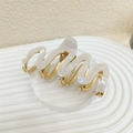 Detail shot of wavy pearlized acetate hair claw clip with golden metal base and teeth - Pearl White