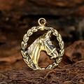 Primer plano de un colgante de cabeza de caballo dorado vintage con detalles de metal - Colgante de Acero con Dorado y Negro