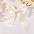 Creamy white satin bow hair clip with long ribbons on a decorative ceramic plate - Cream White