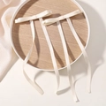 Pair of off-white matte satin hair bows with long streamers on a wooden tray - Off White