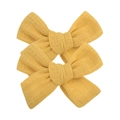 Detail of two yellow fabric bow hair clips with textured linen material on white background - Ginger (49)