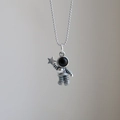 Macro shot of silver astronaut pendant featuring a star and black enamel helmet detail - Star-catching Astronaut / Bead Chain