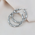 Vue détaillée de créoles torsadées argentées au fini poli sur un tissu texturé doux - Double Torsion (Argent 30mm)