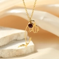 Detalle del collar con colgante de flor dorada y circón rojo sobre un fondo de piedra - Flor de Enero / Dorado