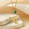 Macro shot of gold stainless steel necklace with blue rhinestone and leaf pendant - Birth Flower