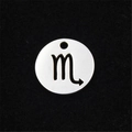 Macro detail of a silver stainless steel round pendant with Scorpio zodiac cutout design - Scorpio