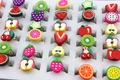 Detailansicht verstellbarer Kinderringe mit bunten Fruchtmotiven in einer weißen Verkaufsbox - Einstellbar Offen / Obst-Stil