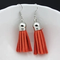 Vue détaillée de boucles d'oreilles à pompons orange avec crochets argentés sur céramique - Orange (D)