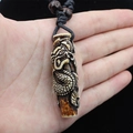 Detailed view of hand-held vintage resin dragon totem pendant with braided cord and beads - Red Brown