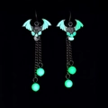 Detailed view of luminous bat skull earrings with glowing green beads in the dark - Green Glow Devil Wing
