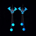 Luminous gothic earrings with blue glowing bat wings and skeleton in dark background - Blue Glow Devil Wing