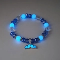Macro detail van de walvisstaart hanger en lichtgevende blauwe kralen op armband - Blauw