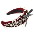 Dettaglio di un cerchietto in velluto rosso con strass scintillanti e fiocco di raso nero - Rosso