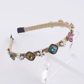 Dettaglio del cerchietto intrecciato dorato con pietre colorate e fiori di perle - Strass Colorato Perla