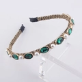 Detailed macro view of vintage gold headband with green gems and white pearls - Green