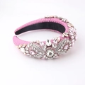 Detail eines rosa Barock-Schwammstirnbands mit funkelnden Kristallen und Textur - Rot
