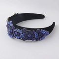 Close-up of blue crystals and floral beads on a black velvet baroque headband - Blue