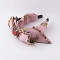 Close-up of Baroque pink floral headband with large red rhinestone and pearl details - Pink