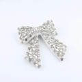 Dettaglio del fermaglio a fiocco con strass lussuosi, base in metallo e velluto - Bianco