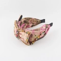Dettaglio di un'ampia fascia rosa a nodo con strass colorati e spilla a insetto vintage - Rosa Oro (C)