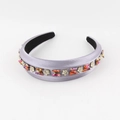 Detail eines lila Satin-Haarreifs mit Strass-Schmetterlingen und Blumenakzenten - Lila
