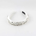 Close-up of white satin headband with crystal flower pattern and hand made label details - White