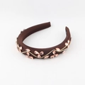 Macro detail of brown padded headband featuring wave rhinestone chain and pink crystal petals - Coffee