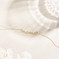 Elegante pulsera MAMA bañada en oro de 14k con circonitas brillantes sobre fondo crema - Collar de Letras MAMA (XL0178)