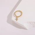 Macro shot of gold beaded ring with sparkling zircon cross pendant on a white rock - One Size / Style 2